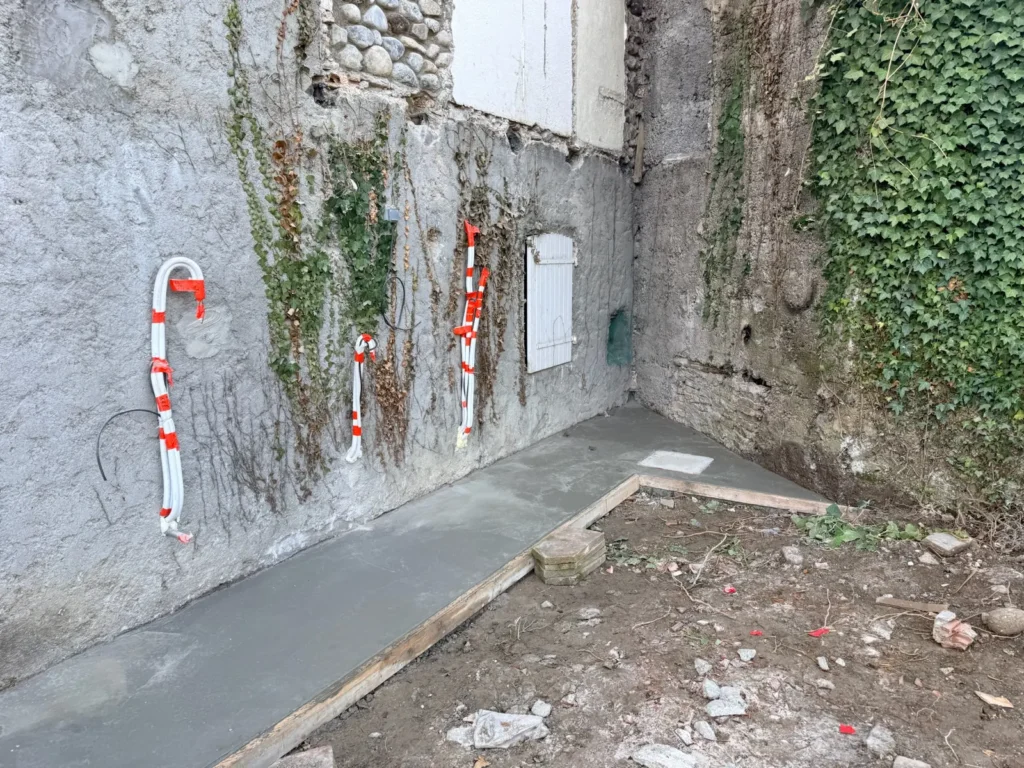 Réseaux et gaines en attente au pied de la façade en galets