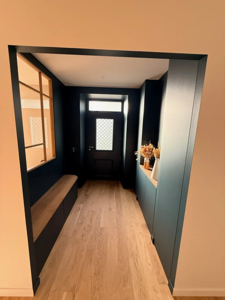 Couloir d'entrée rénové avec banc et murs bleu nuit
