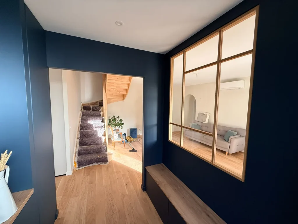 Entrée rénovée avec verrière d'atelier et vue sur l'escalier neuf