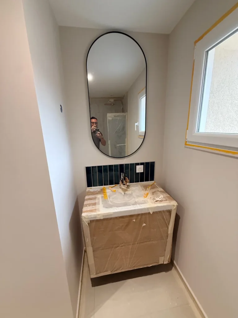 Salle d'eau rénovée avec meuble vasque en bois et miroir arrondi