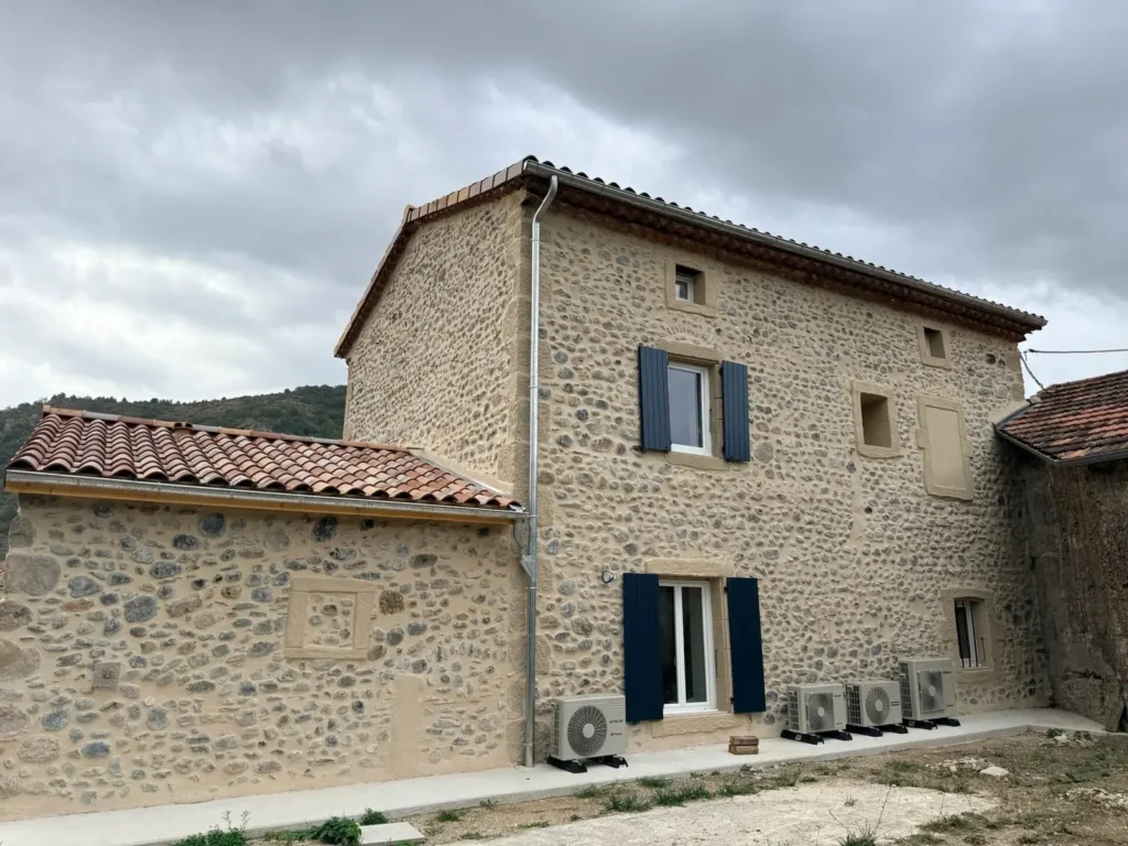 Façade nord et annexe en galets après rénovation, toiture en tuiles canal